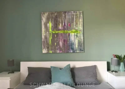 Modernes Schlafzimmer der Ferienwohnung Waldwiese mit großem abstraktem Kunstbild.