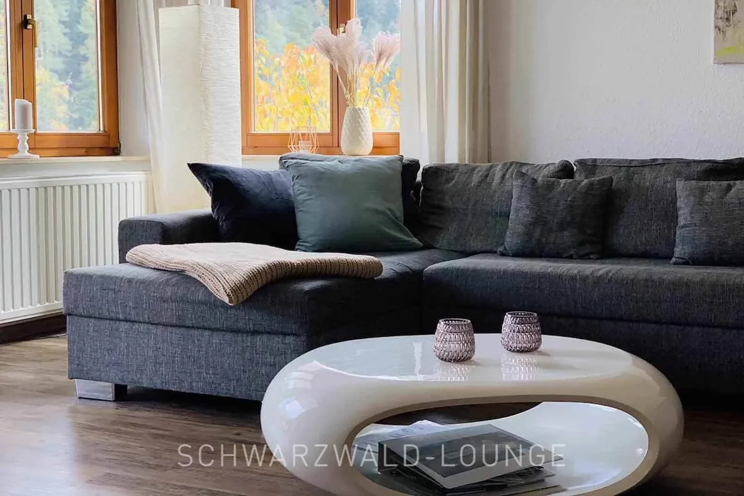 Wohnzimmer der Ferienwohnung Waldwiese mit modernem Ecksofa und stilvollen Wohnaccessoires.