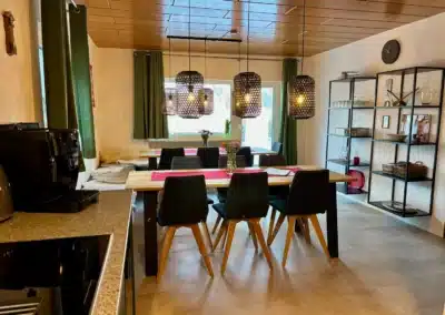 Essbereich mit Tageslicht, Holztischen und Fensterfront im Ferienhaus Tanne und Tal Relax