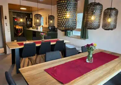 Großer Essbereich mit Massivholztischen und schwarzen Pendelleuchten im Ferienhaus Tanne und Tal Relax