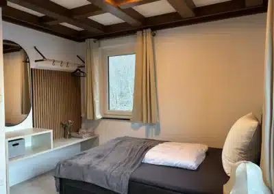 Detailansicht Schlafzimmer mit Bett, Fenster und Holzdecke im Ferienhaus Tanne und Tal Relax im Schwarzwald.