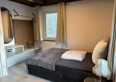 Schlafzimmer mit Einzelbett, Fenster und ruhiger Einrichtung im Ferienhaus Tanne und Tal Relax.