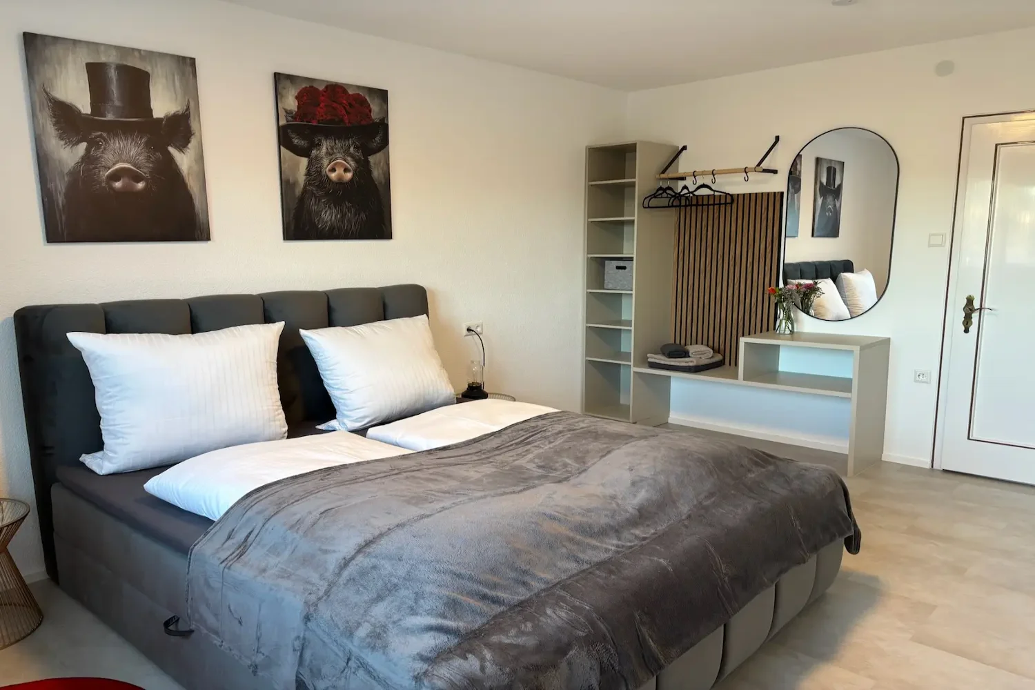 Modernes Schlafzimmer mit Doppelbett, Stauraum, Garderobe und dekorativen Wandbildern im Ferienhaus Tanne und Tal Relax im Schwarzwald.
