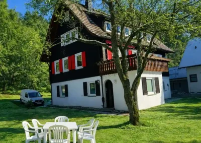 Sommerliche Fassadenansicht von Tanne und Tal Relax mit Sitzgruppe im Garten, Balkon und altem Baumbestand