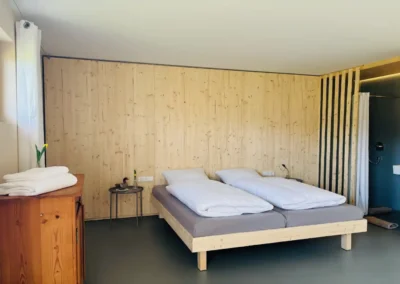 Schlafzimmer im Ferienhaus Baiersbronn Weitblick mit Holzwand und offenem Badbereich