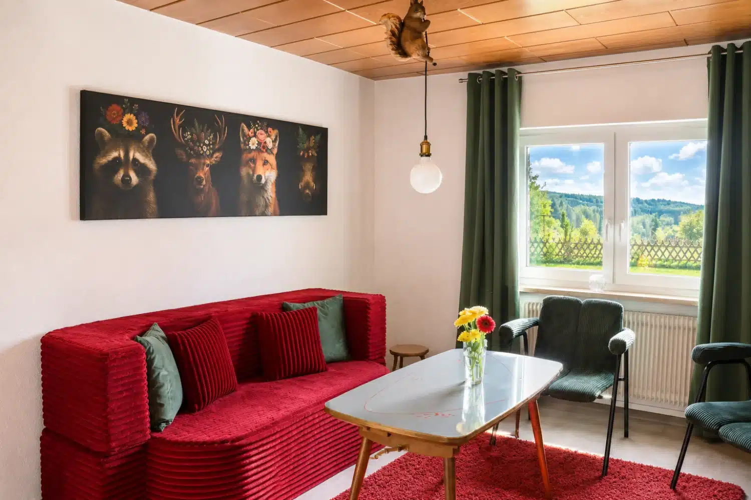 Aufenthaltsraum im Ferienhaus Tanne und Tal Relax mit rotem Sofa, Sesseln und Blick in den Schwarzwald