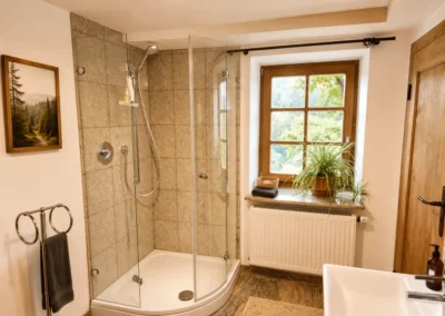 Badezimmer mit Runddusche, Fensterblick und Holzelementen im Refugium am Ursprung