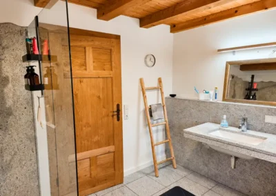Modern-rustikales Badezimmer mit Waschtisch, Dusche und Holzbalkendecke im Refugium am Ursprung