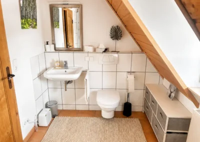 Kleines Badezimmer im Dachgeschoss mit Waschbecken, WC und Dachschräge im Refugium am Ursprung