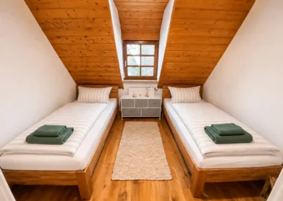Dachgeschoss-Zweibettzimmer mit zwei Einzelbetten und grünen Handtüchern im Refugium am Ursprung - für eine Auszeit im Schwarzwald