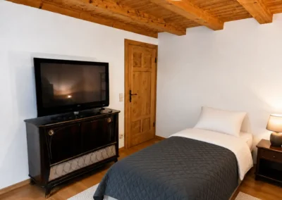 Einzelzimmer mit TV, Holzbalkendecke und gemütlichem Bett im Refugium am Ursprung - für eine Auszeit im Schwarzwald