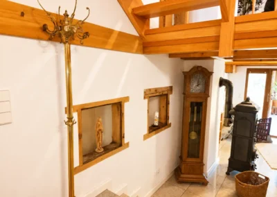 Flur mit Treppe, Holzelementen, Standuhr und Ofenblick im Refugium am Ursprung
