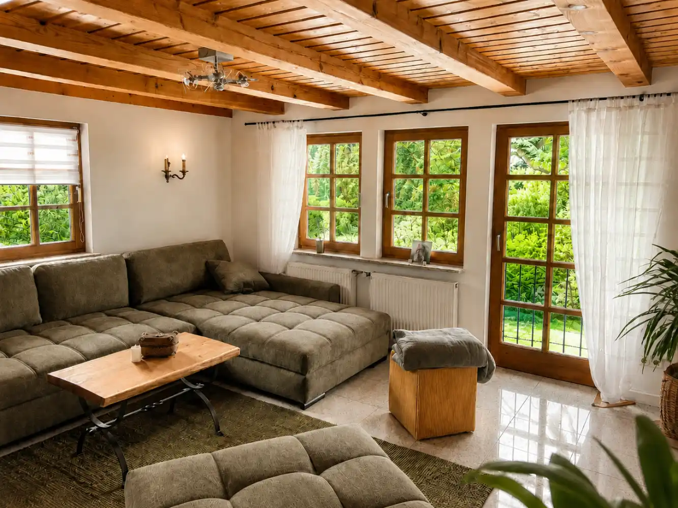 Refugium am Ursprung – Wohnzimmer mit Blick ins Grüne Wohnzimmer mit großem Sofa, Holzbalkendecke und Gartenzugang im Refugium am Ursprung